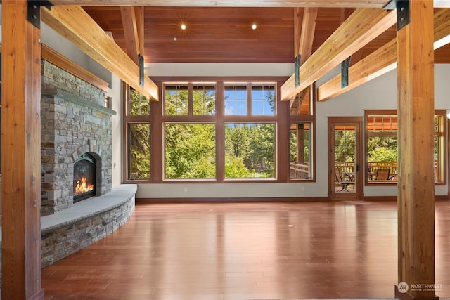 sunroom / solarium featuring vaulted ceiling with beams, wood ceiling, plenty of natural light, and a stone fireplace