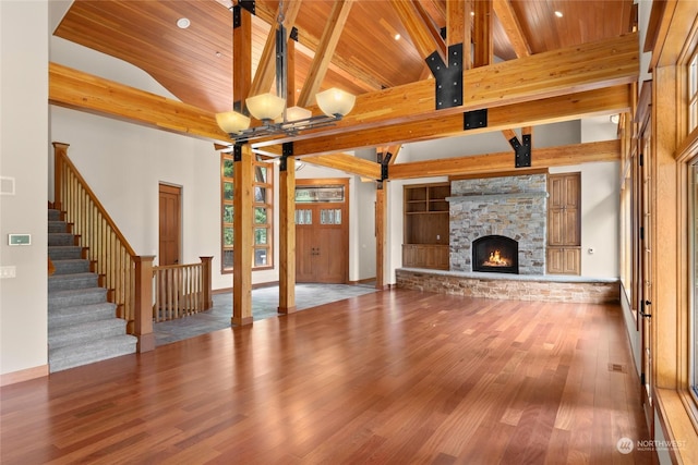 unfurnished living room with beam ceiling, stairway, wood finished floors, high vaulted ceiling, and wooden ceiling