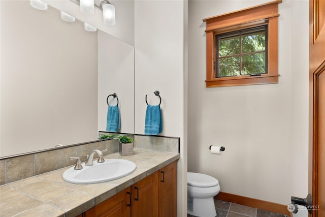 bathroom with toilet, baseboards, and vanity