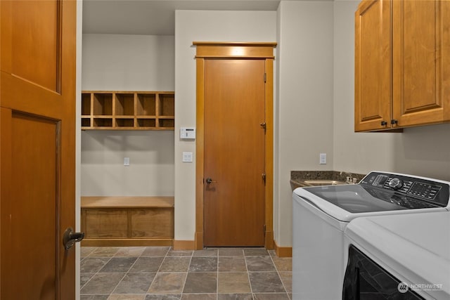 laundry room with cabinet space, stone finish floor, a sink, washer and dryer, and baseboards