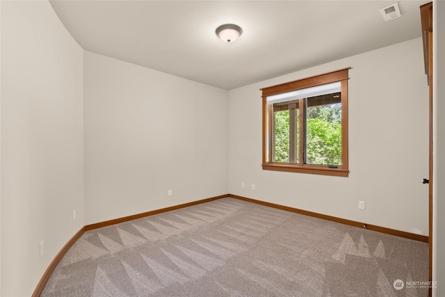 spare room with carpet flooring, visible vents, and baseboards