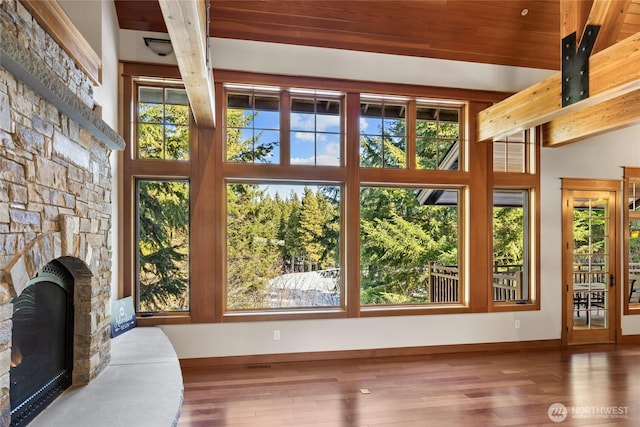 living area featuring a fireplace, wood finished floors, beam ceiling, and baseboards