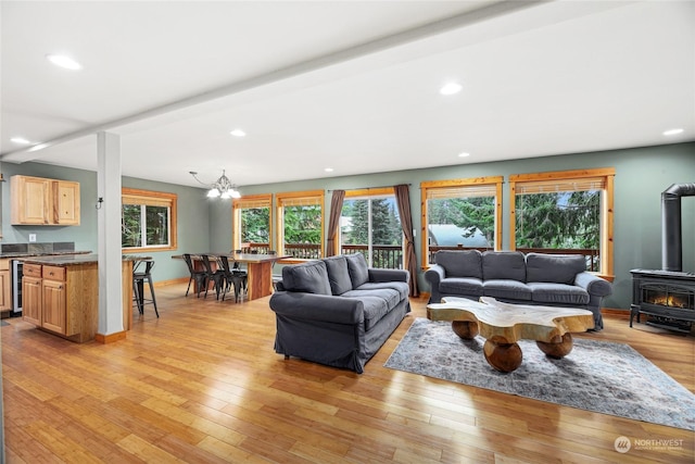 living room featuring an inviting chandelier, light wood-type flooring, beverage cooler, and a wood stove