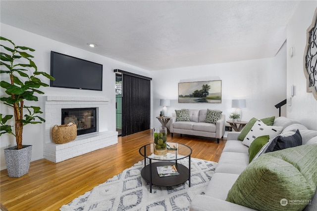 living room featuring a fireplace, a textured ceiling, and light wood-type flooring