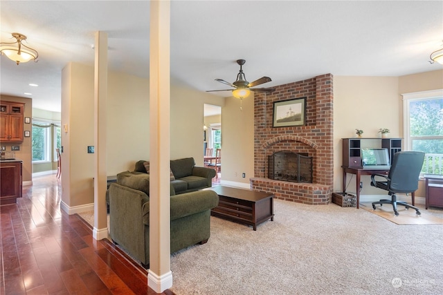 living room featuring a brick fireplace, dark carpet, sink, and ceiling fan