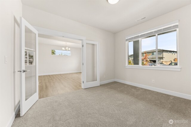 spare room featuring carpet flooring, a chandelier, and french doors