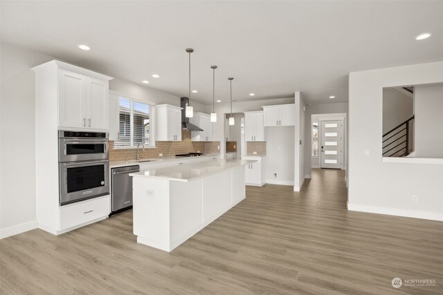 kitchen with sink, decorative light fixtures, a center island, stainless steel appliances, and white cabinets