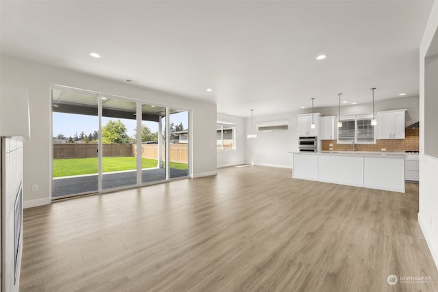 unfurnished living room with sink and light hardwood / wood-style flooring