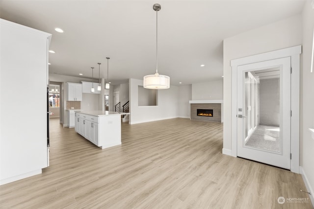 kitchen with white cabinetry, hanging light fixtures, light hardwood / wood-style floors, and a kitchen island