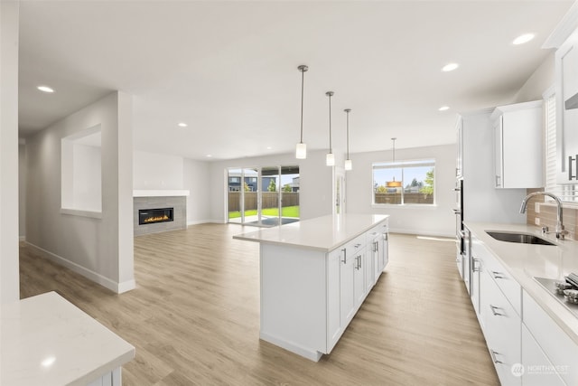 kitchen with white cabinetry, decorative light fixtures, sink, and a kitchen island