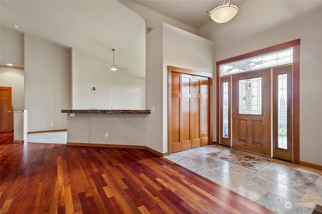 foyer entrance featuring wood-type flooring and high vaulted ceiling