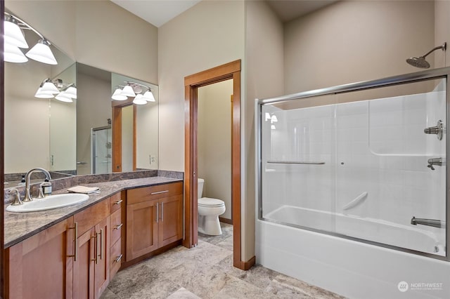 full bathroom with vanity, bath / shower combo with glass door, and toilet