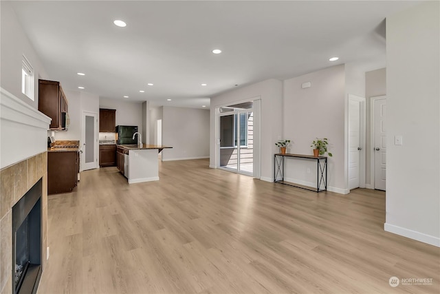 living room with sink, a fireplace, and light hardwood / wood-style floors