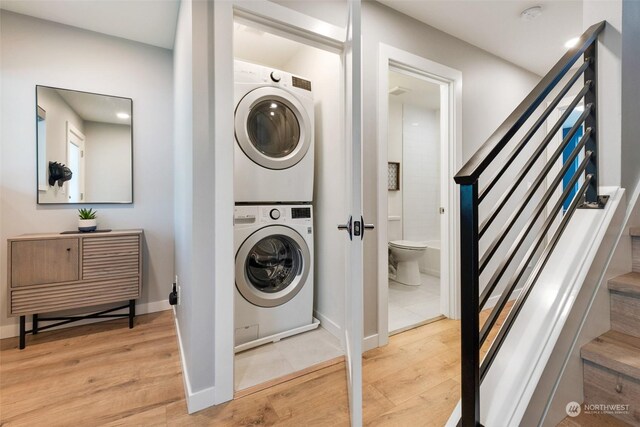 clothes washing area featuring light hardwood / wood-style flooring and stacked washer and dryer