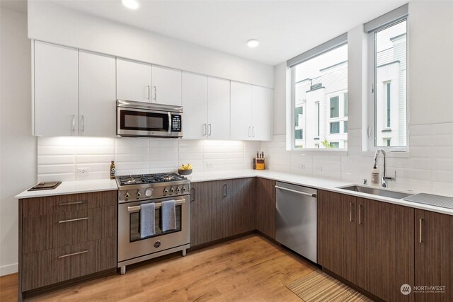 kitchen featuring backsplash, appliances with stainless steel finishes, light wood-type flooring, and white cabinetry