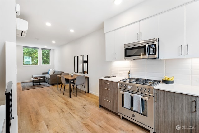 kitchen featuring appliances with stainless steel finishes, white cabinets, dark brown cabinetry, light hardwood / wood-style floors, and tasteful backsplash