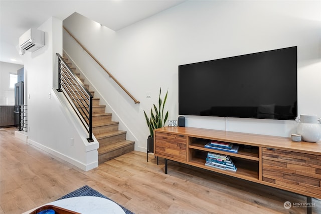 living room featuring a wall mounted air conditioner and light hardwood / wood-style floors