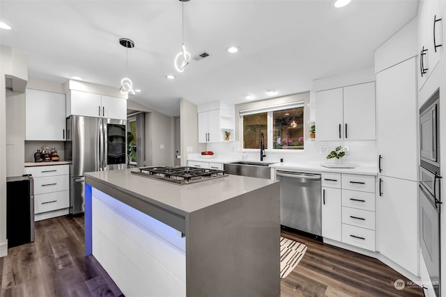 kitchen featuring dark wood-type flooring, stainless steel appliances, sink, and a center island