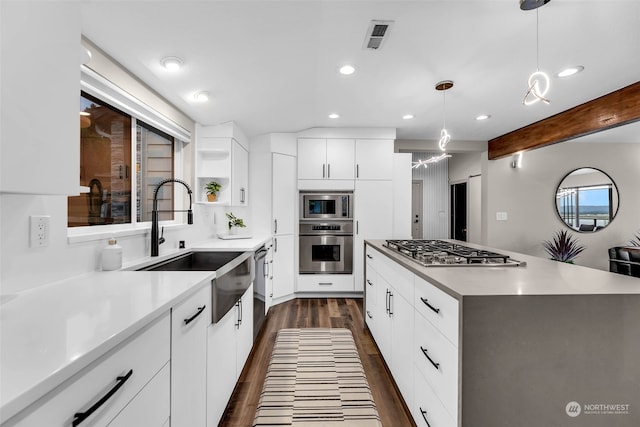 kitchen featuring white cabinetry, appliances with stainless steel finishes, dark wood-type flooring, beamed ceiling, and a kitchen island