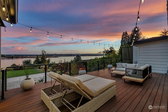 deck at dusk with an outdoor hangout area and a water view