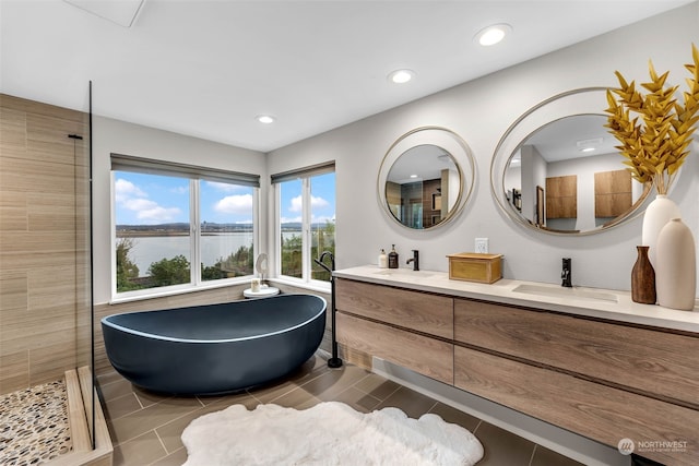 bathroom with tiled shower, a water view, double vanity, and tile patterned flooring