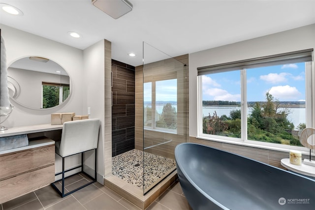 bathroom with shower with separate bathtub, a water view, plenty of natural light, and tile patterned flooring