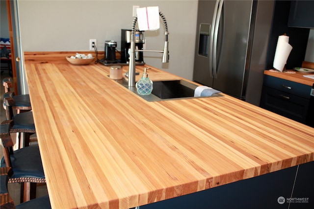 kitchen featuring wood-type flooring, wood counters, and stainless steel fridge