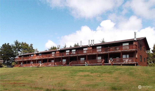 back of property featuring a wooden deck and a lawn