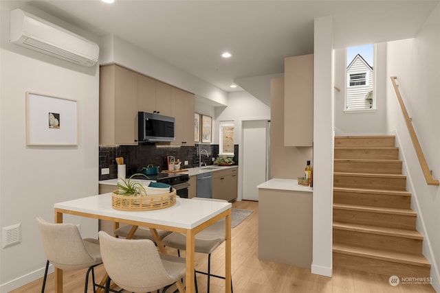 kitchen featuring stainless steel appliances, light hardwood / wood-style floors, gray cabinets, and a wall unit AC