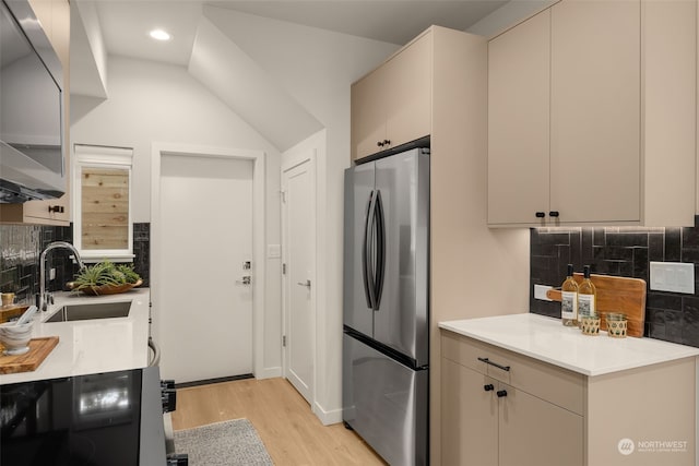 kitchen with sink, light hardwood / wood-style floors, decorative backsplash, and stainless steel fridge