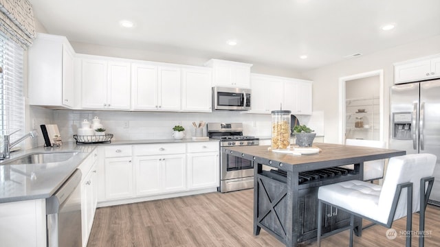 kitchen featuring white cabinets, stainless steel appliances, light hardwood / wood-style flooring, and sink