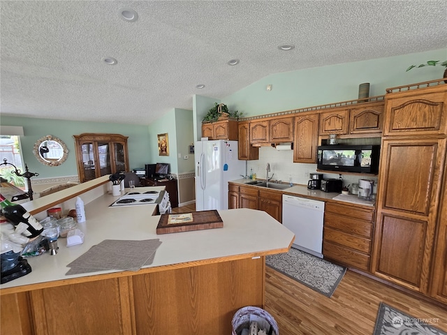 kitchen featuring white appliances, a textured ceiling, lofted ceiling, light hardwood / wood-style flooring, and sink