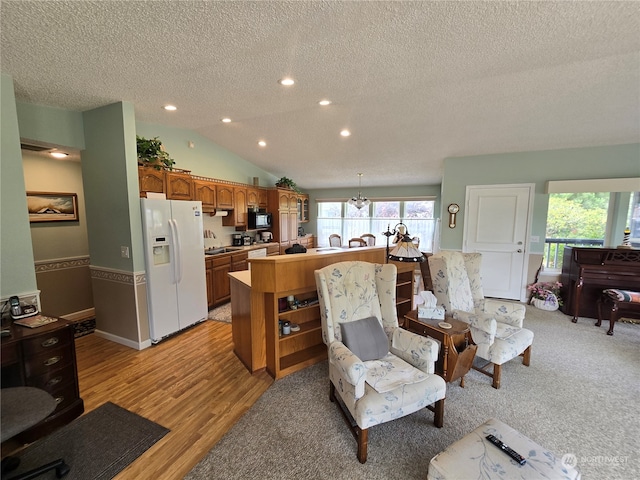 living room featuring light wood-type flooring, vaulted ceiling, and a textured ceiling