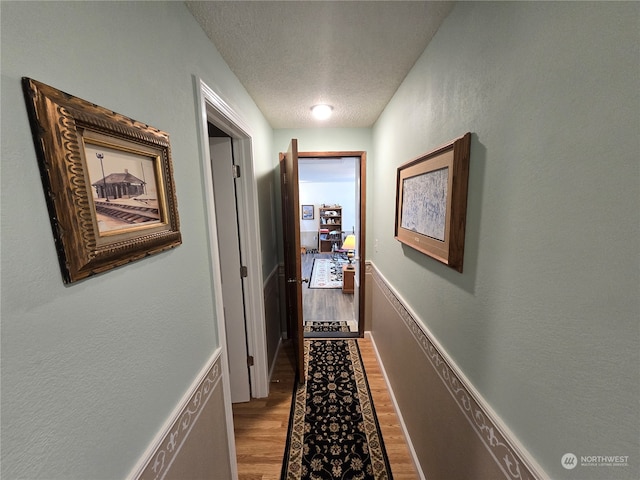 hall featuring a textured ceiling and hardwood / wood-style flooring