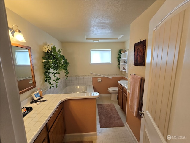 bathroom featuring a textured ceiling, vanity, toilet, and a tub