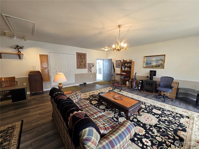 living room featuring a notable chandelier, a wood stove, and dark wood-type flooring