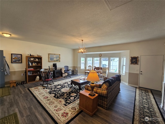 living room featuring an inviting chandelier, a textured ceiling, wood walls, and dark hardwood / wood-style flooring