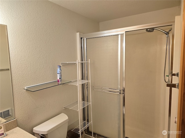 bathroom featuring a textured ceiling, a shower with shower door, and toilet