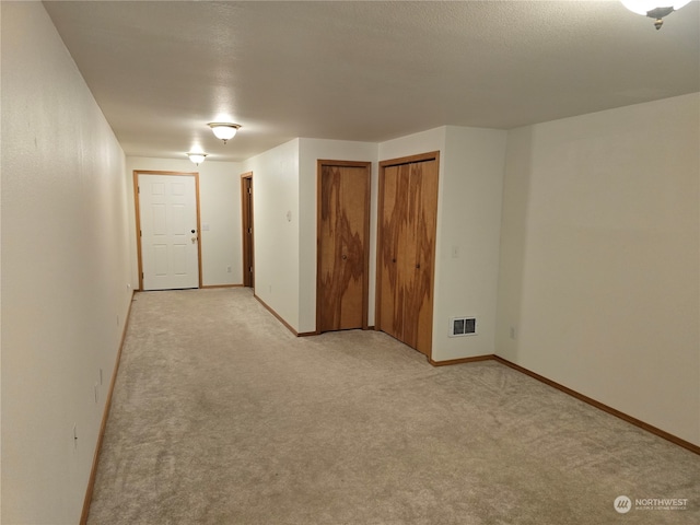 empty room with a textured ceiling and light carpet