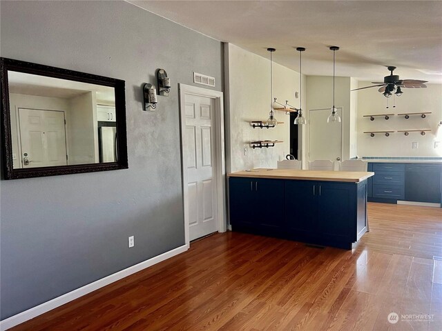 kitchen featuring hardwood / wood-style flooring, ceiling fan, a breakfast bar area, kitchen peninsula, and fridge