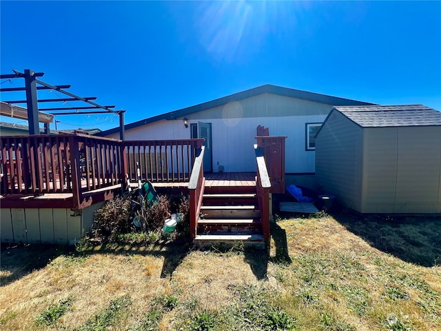 rear view of property featuring a pergola, a wooden deck, and a lawn