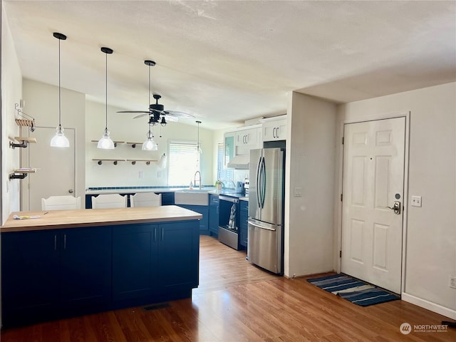 kitchen featuring ceiling fan, light wood-type flooring, hanging light fixtures, blue cabinets, and stainless steel appliances