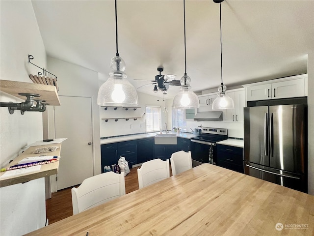 kitchen with stainless steel appliances, wall chimney exhaust hood, white cabinets, blue cabinets, and hardwood / wood-style flooring