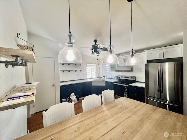 kitchen with pendant lighting, stainless steel appliances, light countertops, white cabinets, and wall chimney exhaust hood