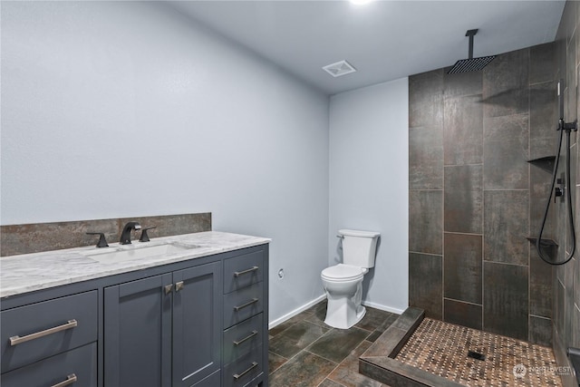 bathroom with vanity, toilet, and a tile shower