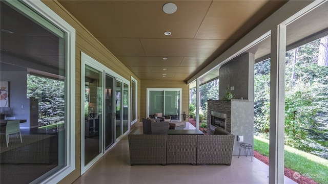 unfurnished sunroom featuring an outdoor stone fireplace