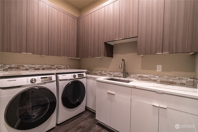 laundry room featuring washing machine and clothes dryer, sink, dark wood-type flooring, and cabinets