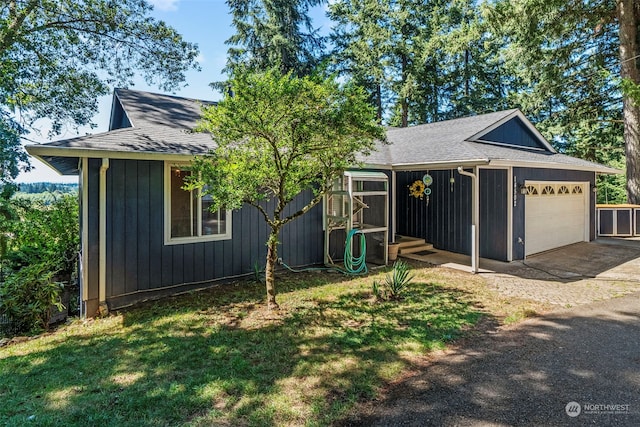 view of front of home with a garage, roof with shingles, driveway, and a front lawn