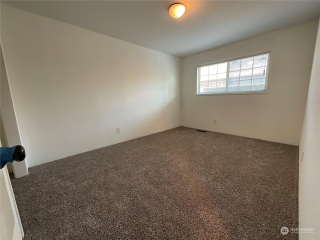 unfurnished room with dark carpet