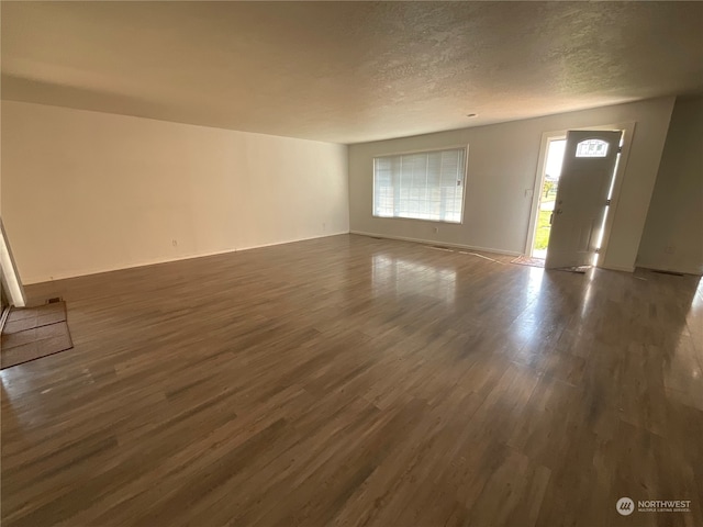 unfurnished living room featuring dark hardwood / wood-style floors and a textured ceiling